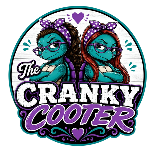 A circular sticker or graphic design featuring two cartoon turtles with purple polka-dot bows and glasses, one with brown hair and one with red hair. Large stylized text reads 'The CRANKY COOTER' in white and purple on a white wood-plank background, with teal and purple decorative accents.